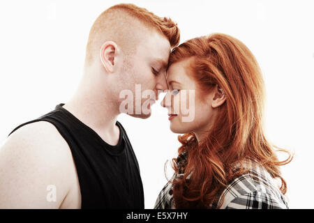 Studio portrait of red haired young couple head to head with eyes closed Stock Photo