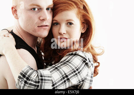 Studio portrait of red haired young couple hugging cheek to cheek Stock Photo