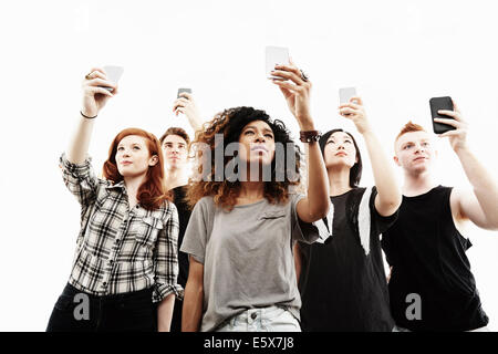 Studio portrait of five young adults taking selfies on smartphones Stock Photo