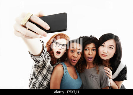Studio portrait of four young women taking selfie on smartphone Stock Photo
