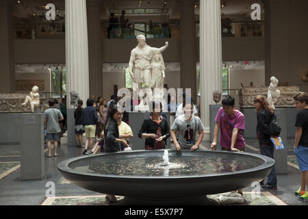 Young Chinese tourists make a wish in the fountain in the Greek & Roman galleries at the Metropolitan Museum in NYC. Stock Photo