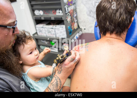 Tattoo artist showing toddler how to give a tattoo Stock Photo