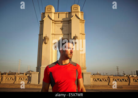Young male runner taking a break at city bridge Stock Photo
