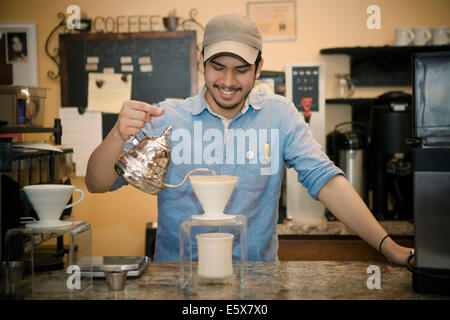 Barista pouring tea through filter to cup on cafe counter Stock Photo