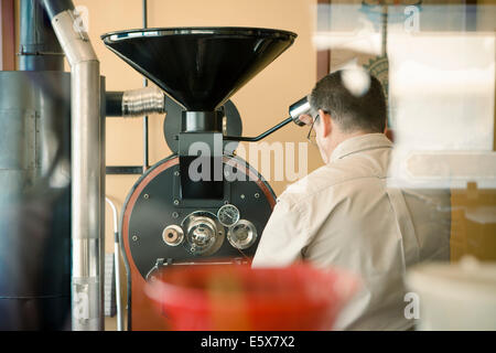 Rear view of mature man using coffee roasting machine in cafe Stock Photo