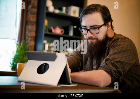 Young man having coffee and using digital tablet in cafe Stock Photo