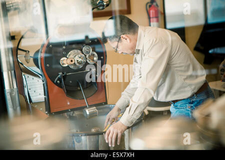 Mature man using coffee roasting machine in cafe Stock Photo
