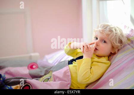 Male toddler lying in bed making secret hand gesture sign Stock Photo