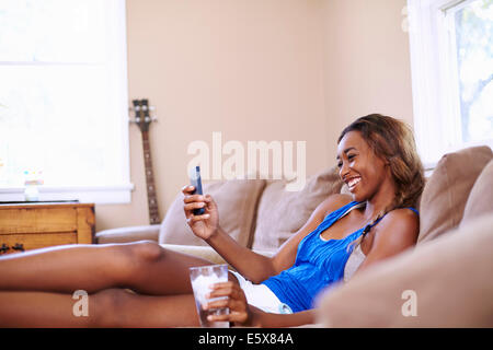 Young woman on a training break, looking at smartphone in sitting room Stock Photo