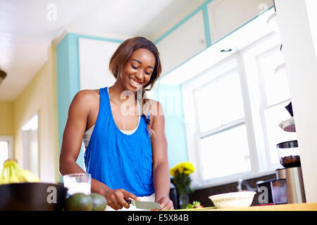 Young woman taking a training break, preparing food in kitchen Stock Photo