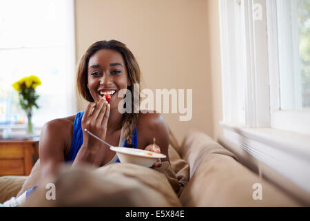 Young woman on a training break, eating fruit on sofa Stock Photo