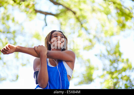Young female runner stretching arms in park Stock Photo