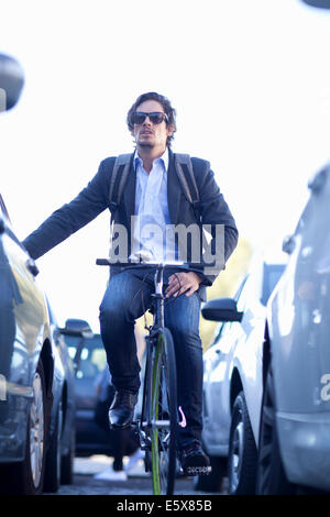 Mid adult businessman cycling in traffic congestion Stock Photo
