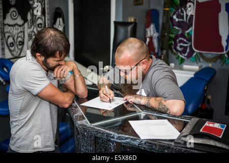 Artist drawing up tattoo ideas with a client Stock Photo