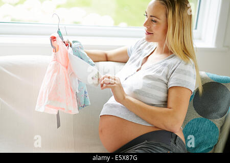 Pregnant woman looking at baby clothes Stock Photo