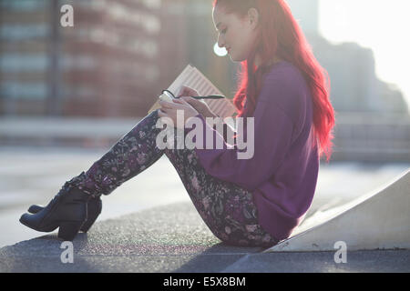 Young woman writing in notebook on city rooftop parking lot Stock Photo