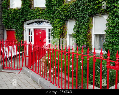 Georgian house on the Octagon, Westport Town, County Mayo, Connaught, Republic of Ireland with vivid red door and iron railings. Stock Photo