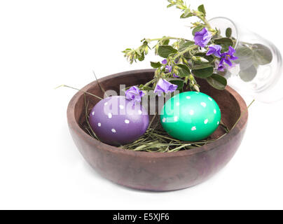 Polka dot dyed eggs in a bowl with field flowers over white background Stock Photo