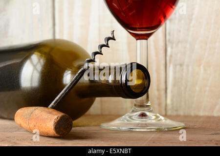 Wine still life with a bottle on its side and the bottom of a glass of red wine and a cork screw leaning on the bottle.  Horizon