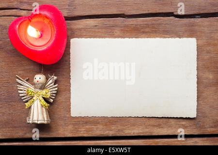 holiday background with blank vintage postcard, burning candle and toy angel Stock Photo