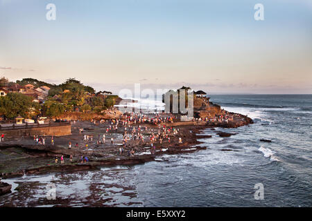 Tourists flock to the sacred pilgrimage temple of Tanah Lot in Bali. A travel destination and famous place popularized by the rock temple in the sea Stock Photo