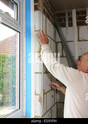 Plasterer fixing corner beading prior to plastering a room in a new property / extension Stock Photo