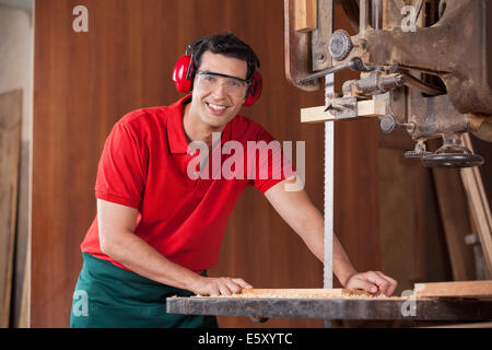 Confident Carpenter Using Bandsaw To Cut Wood Stock Photo