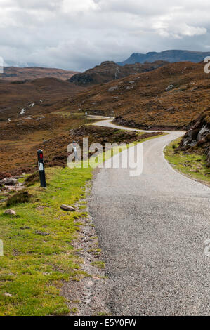 A small winding road shown weaving through the rocky landscape of Western Scotland. Stock Photo