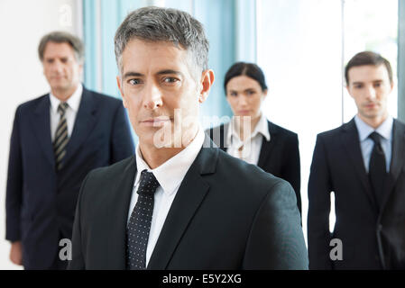 Portrait of four business executives and a young man standing together ...