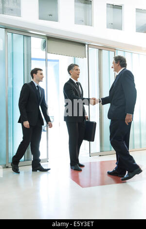 Businessman meeting associates in office lobby Stock Photo