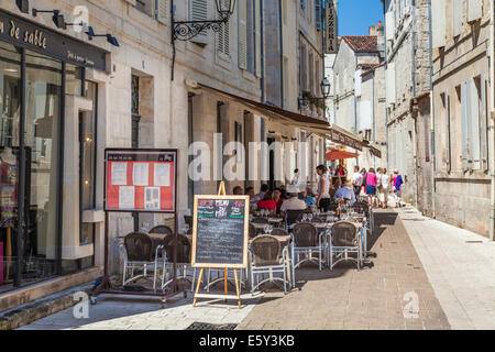 Street restaurant in the shade in a narrow french street. Stock Photo