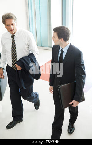 Business associates chatting while entering office building together Stock Photo