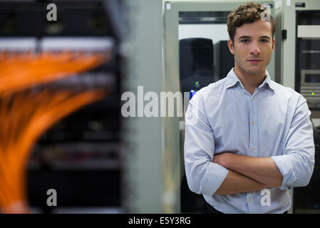 Network cables connected to computer mainframe, computer technician in background Stock Photo