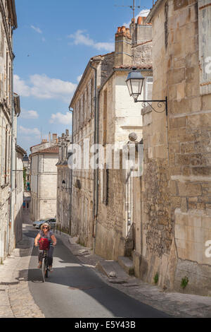 Woman cycling up the steep hill of Rue des Jacobins in Saintes Stock Photo