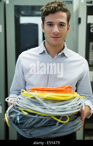 Computer technician carrying coils of networking cables into server room Stock Photo