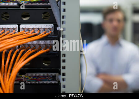 Network cables connected to computer mainframe, computer technician in background Stock Photo