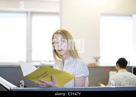 Office worker in office cubicle reviewing file Stock Photo