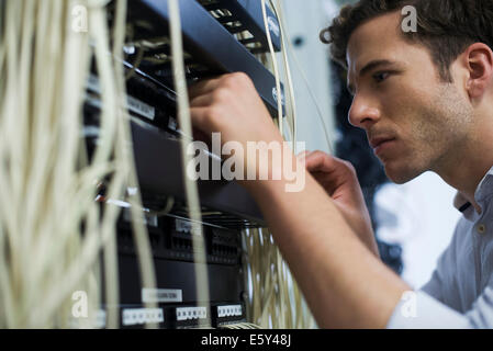 Computer technician performing maintenance on computer networking equipment Stock Photo