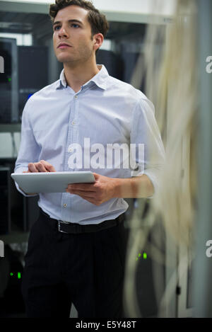Computer technician using digital tablet performing maintenance check of mainframe equipment Stock Photo