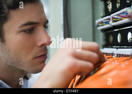 Computer technician performing maintenance work on networking equipment Stock Photo