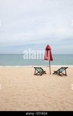 Beach chairs and an umbrella on an empty beach in Thailand Stock Photo