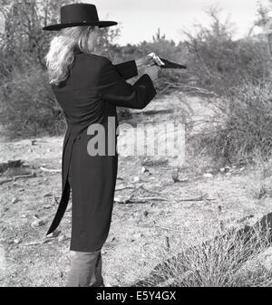 Stock image of a blonde female gunfighter in 1860's outfit out in the desert. Stock Photo