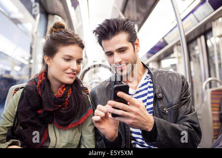 Friends riding subway looking at smartphone together Stock Photo