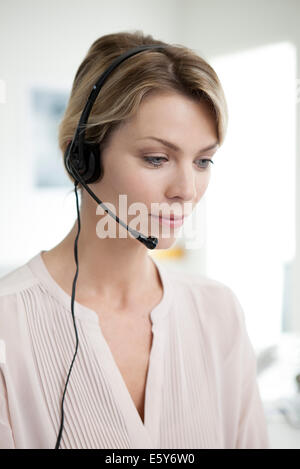 Office worker wearing phone headset multitasking Stock Photo