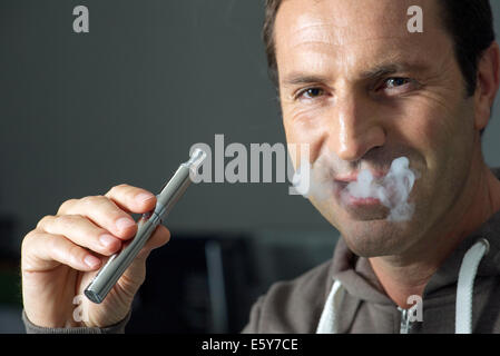 Man smoking electonic cigarette, exhaling smoke Stock Photo