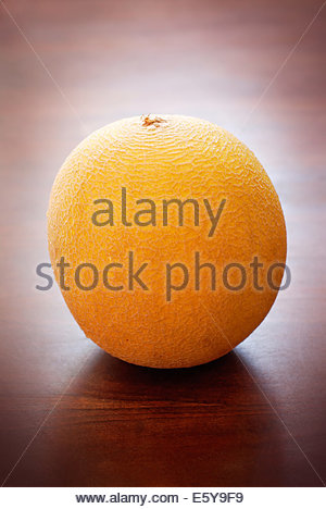 Single yellow galia melon on a wooden tabletop
