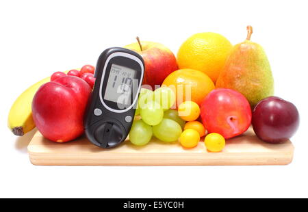 Glucose meter and fresh ripe fruits lying on wooden cutting board, concept for healthy eating and diabetes. Isolated on white ba Stock Photo