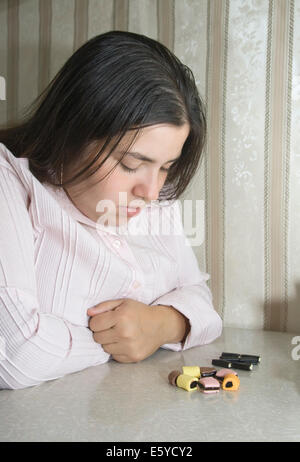 Stout woman contemplating over several sweets Stock Photo