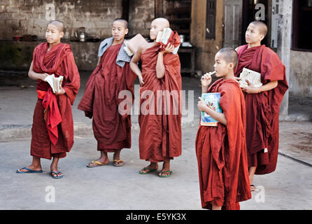 Novice Burmese Buddhist monks listening to a discourse with learning materials at the ready in a Buddhist monastery dressed in traditional robes Stock Photo