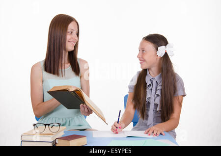 Teacher teaches the student sitting with him at the table Stock Photo